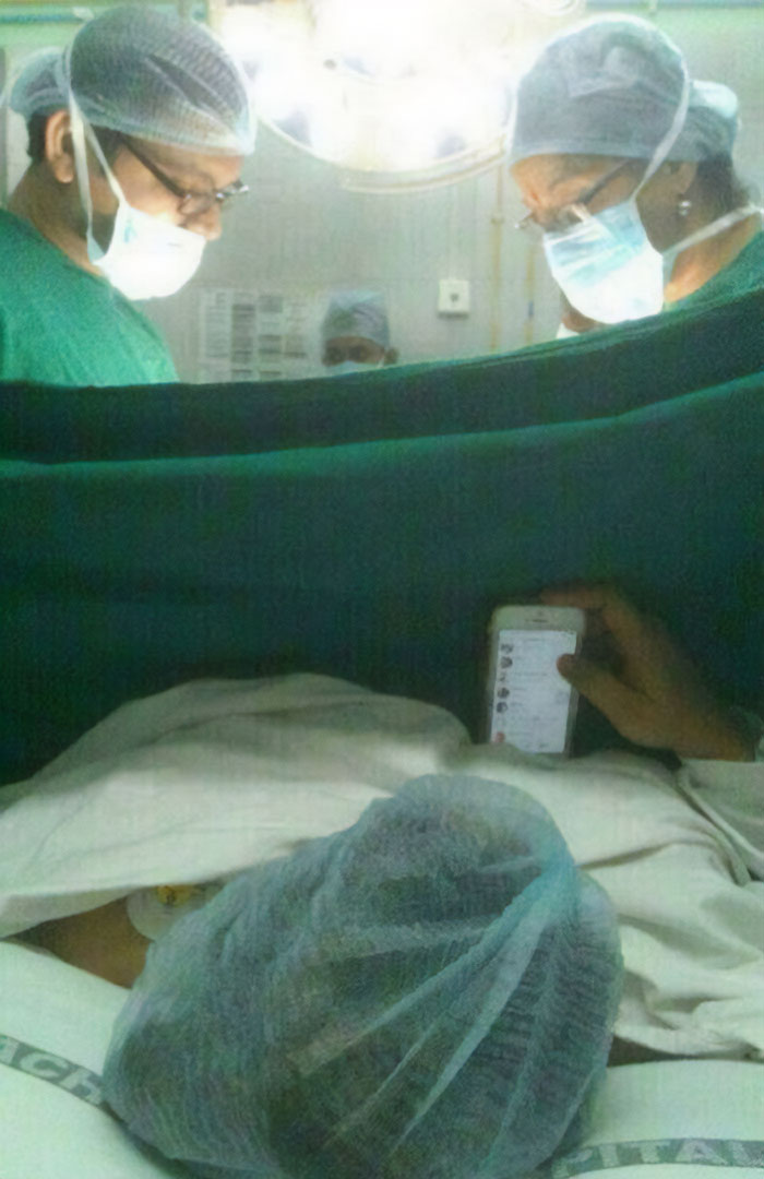 People in surgical attire, a patient holds a phone, creating a moment that makes you go 'hmmm'. People in surgical attire, a patient holds a phone, creating a moment that makes you go 'hmmm'.