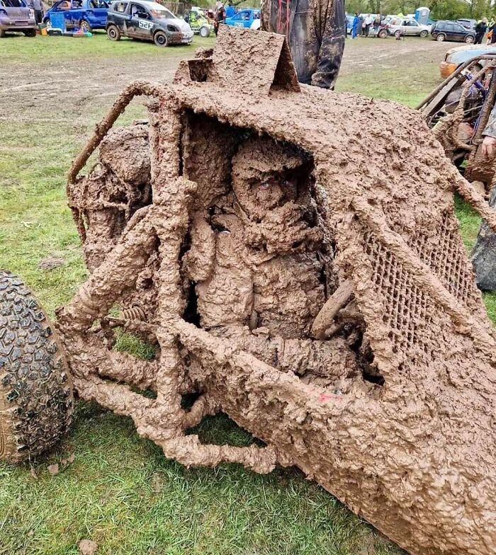 Mud-covered vehicle with driver inside at a muddy field event, capturing a 'Hmmm' moment. Mud-covered vehicle with driver inside at a muddy field event, capturing a 'Hmmm' moment.