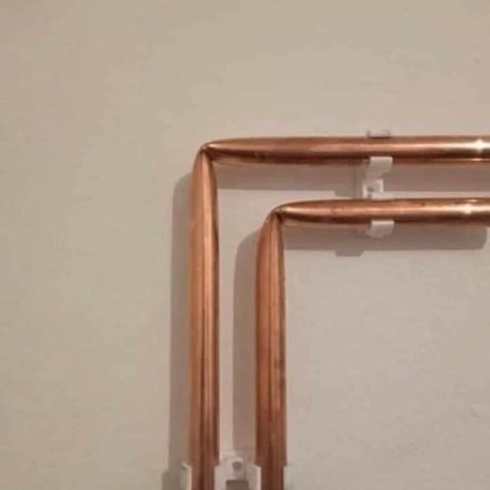 Copper pipes bent at right angles on a wall, making people go "hmmm" with their unusual alignment. Copper pipes bent at right angles on a wall, making people go "hmmm" with their unusual alignment.