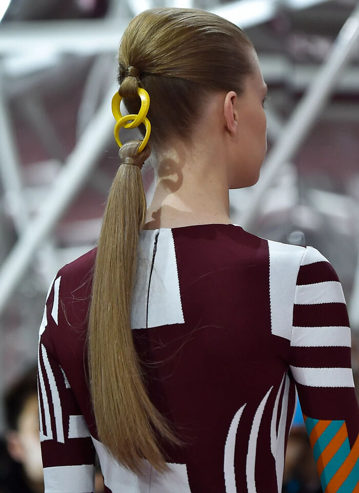 Hairstyle with yellow chain accessory creates a 'hmmm' moment, worn by a person in a patterned outfit. Hairstyle with yellow chain accessory creates a 'hmmm' moment, worn by a person in a patterned outfit.