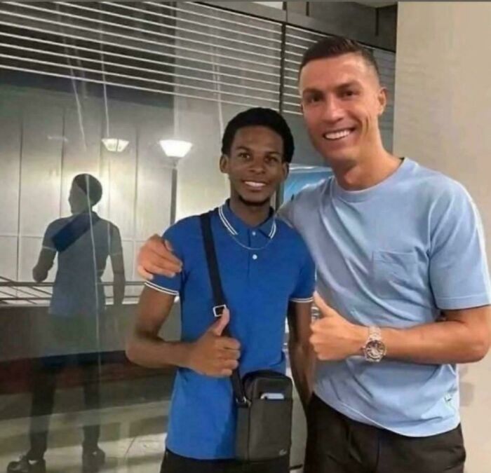 Two people smiling and posing with thumbs up in front of a reflective surface, creating a curious visual effect. Two people smiling and posing with thumbs up in front of a reflective surface, creating a curious visual effect.